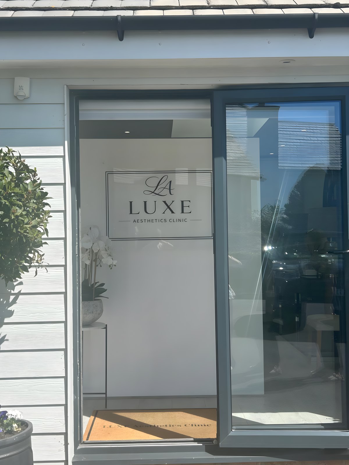 The entrance to Luxe Aesthetics Clinic, with the sign beside the door